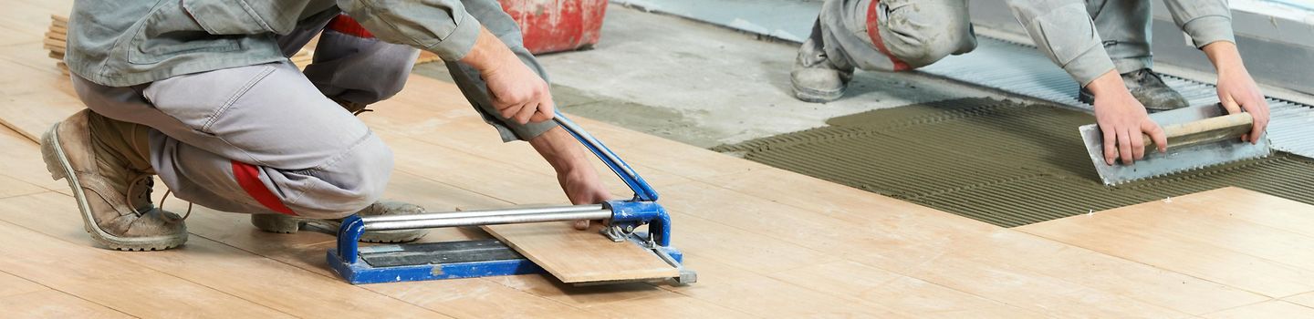 Zwei Arbeiter verlegen einen Fußboden. Zwei Arbeiter verlegen einen Fußboden.