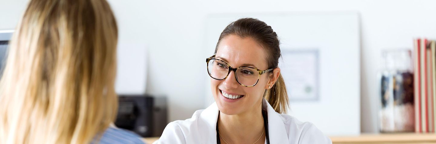 Portrait einer Ärztin im Gespräch mit einer Patientin.