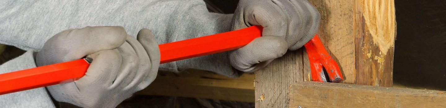 Ein Mann arbeitet mit einer roten Brechstange. Ein Mann arbeitet mit einer roten Brechstange.